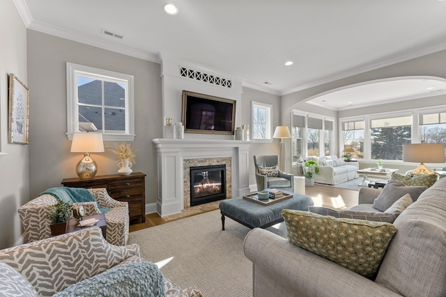 living room with visible vents, a premium fireplace, wood finished floors, crown molding, and recessed lighting