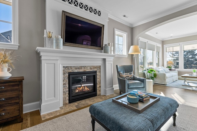 sitting room with a fireplace, wood finished floors, visible vents, baseboards, and crown molding