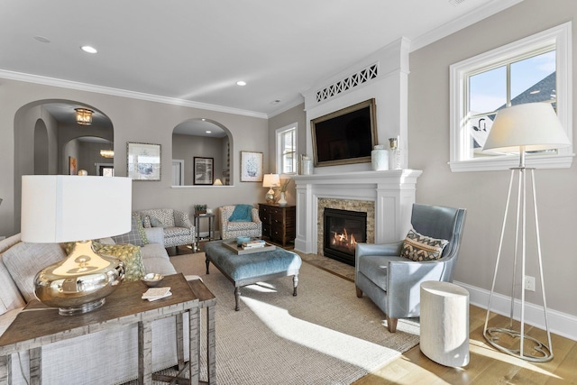 living area with recessed lighting, baseboards, crown molding, and a glass covered fireplace