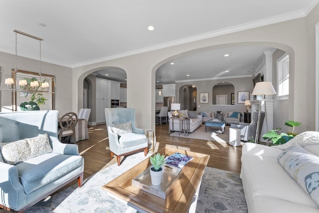 living area featuring a chandelier, ornamental molding, wood finished floors, and recessed lighting