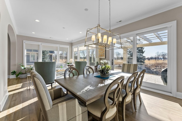 dining room with ornamental molding, arched walkways, visible vents, and wood finished floors