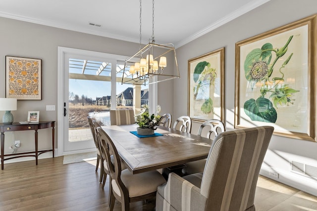 dining area featuring visible vents, a chandelier, crown molding, and wood finished floors