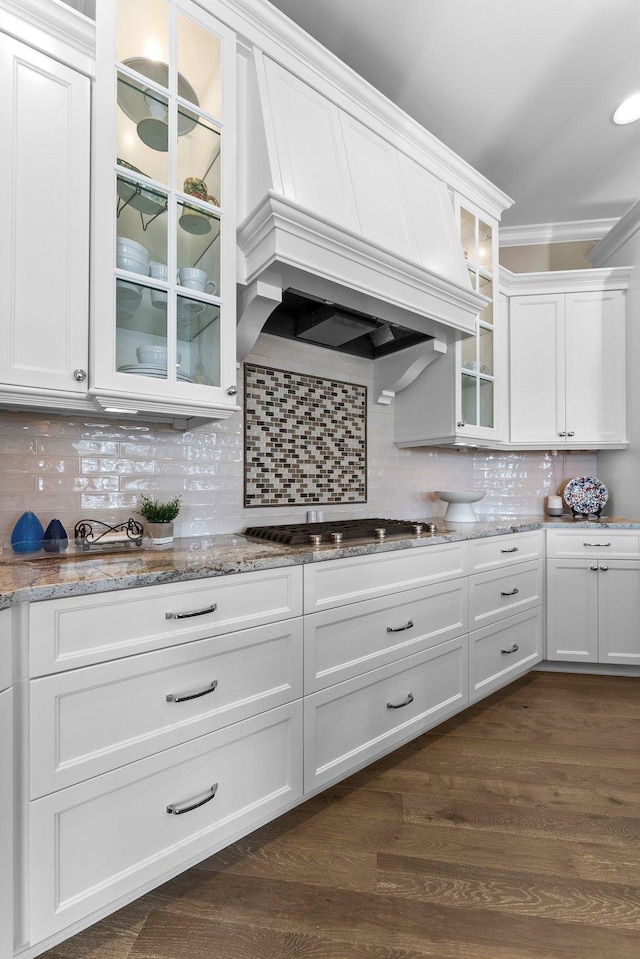 kitchen featuring white cabinets, glass insert cabinets, premium range hood, stainless steel gas stovetop, and backsplash