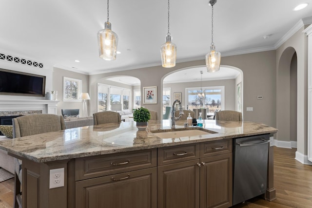 kitchen with a kitchen island with sink, dark wood-type flooring, a sink, open floor plan, and stainless steel dishwasher