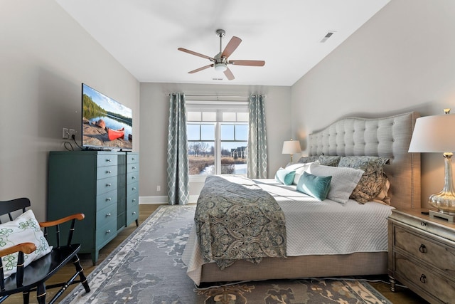 bedroom with a ceiling fan, visible vents, baseboards, and wood finished floors