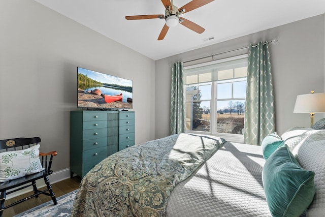 bedroom with a ceiling fan, visible vents, baseboards, and wood finished floors