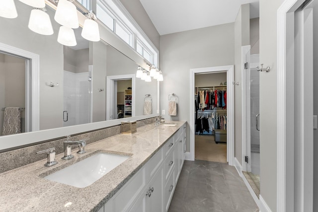 full bathroom featuring double vanity, a shower stall, a spacious closet, and a sink