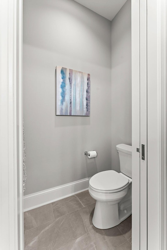 bathroom with tile patterned flooring, baseboards, and toilet