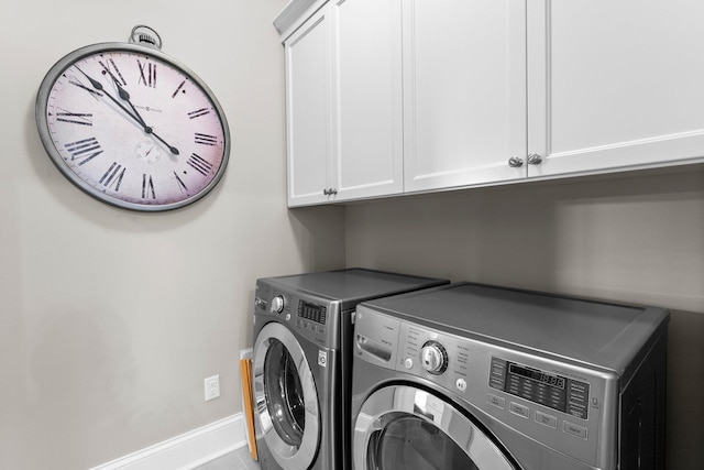 washroom with washing machine and dryer, cabinet space, and baseboards