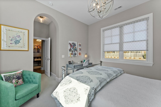 carpeted bedroom with arched walkways, a chandelier, visible vents, and baseboards