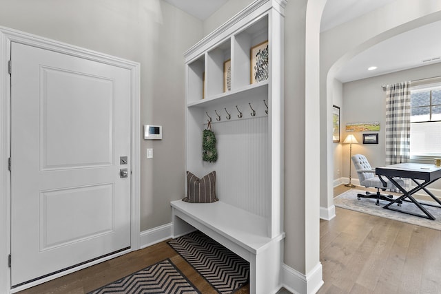 mudroom with arched walkways, baseboards, and wood finished floors