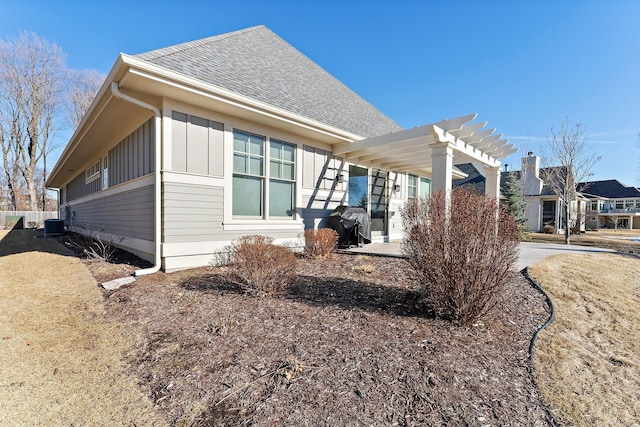 view of home's exterior featuring a shingled roof, a pergola, and board and batten siding