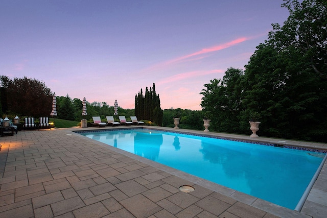 pool at dusk with a patio area