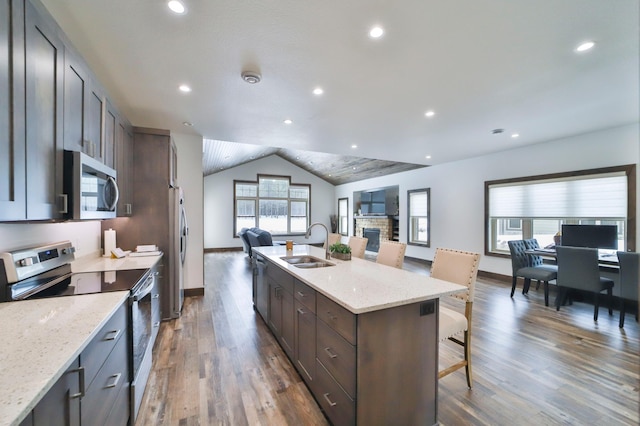 kitchen featuring sink, a kitchen breakfast bar, an island with sink, stainless steel appliances, and light stone countertops