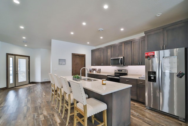 kitchen featuring sink, a breakfast bar area, dark brown cabinets, an island with sink, and stainless steel appliances