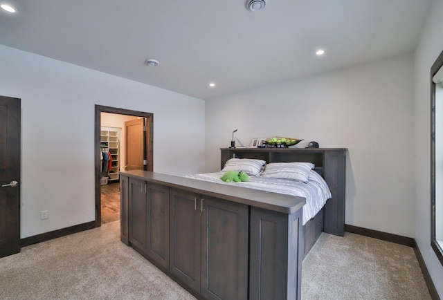 bedroom with light colored carpet and a spacious closet