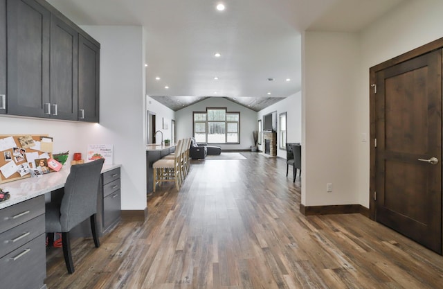 office space with dark wood-type flooring, built in desk, and vaulted ceiling