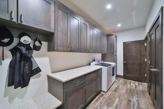 laundry room featuring cabinets, washing machine and clothes dryer, and light wood-type flooring