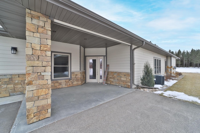 snow covered property entrance with cooling unit and a carport