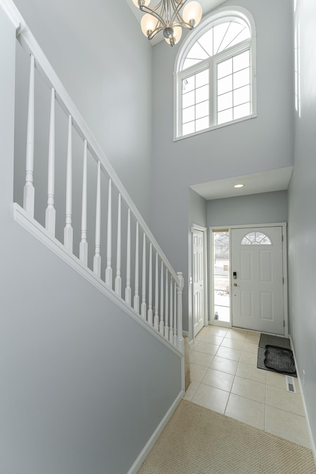 tiled entryway with a chandelier, a healthy amount of sunlight, and a high ceiling