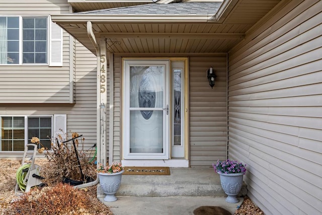 view of exterior entry featuring a shingled roof