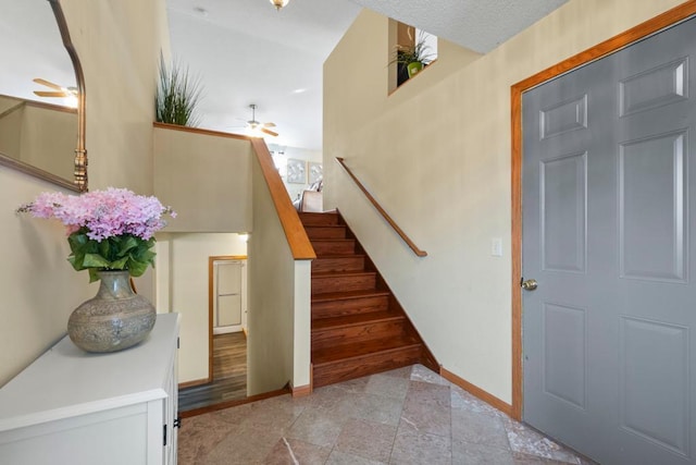 stairway featuring ceiling fan and baseboards