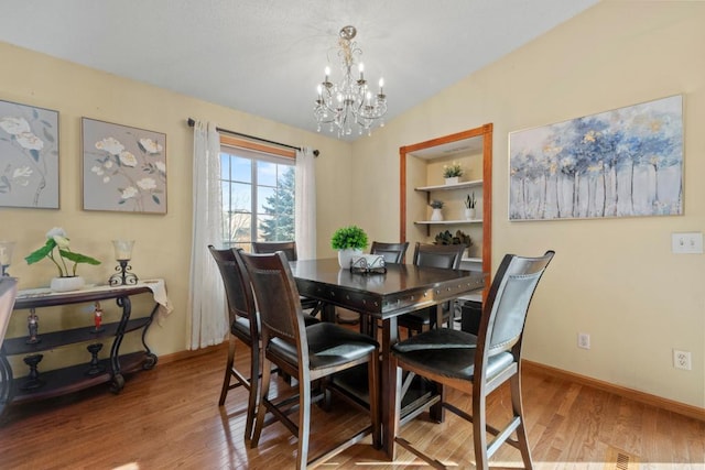 dining area with built in features, lofted ceiling, baseboards, and wood finished floors