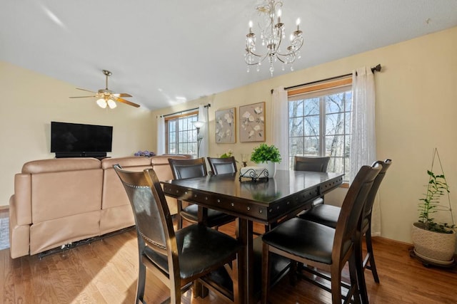 dining space featuring ceiling fan with notable chandelier and wood finished floors