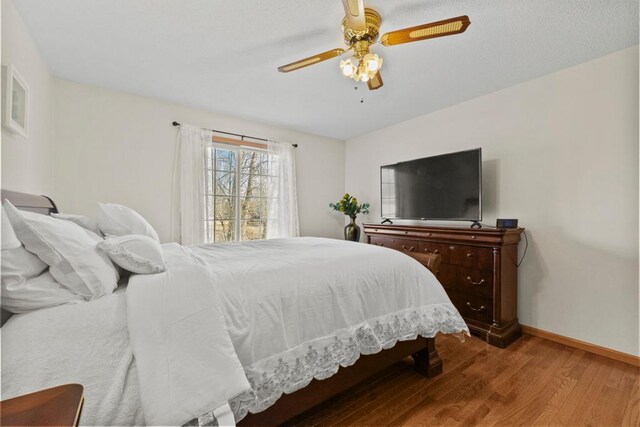 bedroom with a ceiling fan, baseboards, and wood finished floors