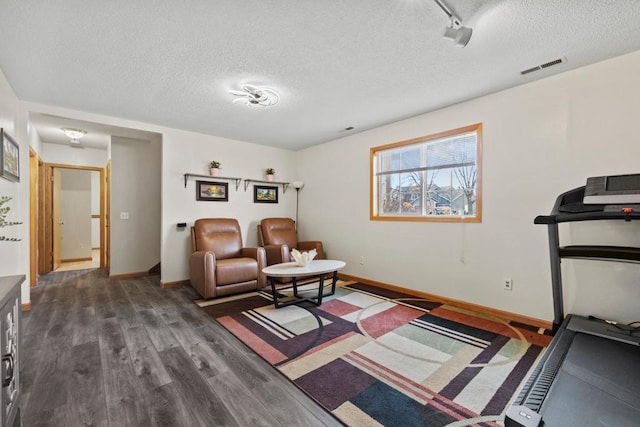 living area featuring dark wood-style floors, baseboards, visible vents, and a textured ceiling