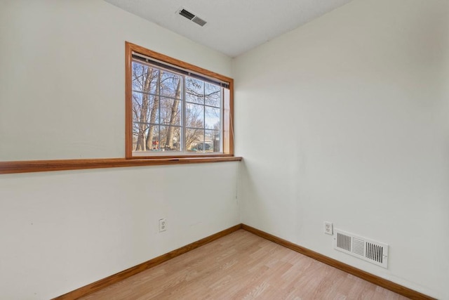 unfurnished room featuring light wood-style floors, visible vents, and baseboards