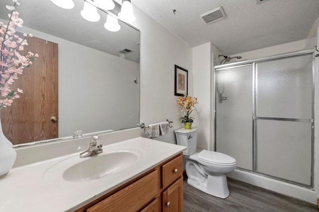 full bathroom with visible vents, toilet, a shower stall, vanity, and wood finished floors