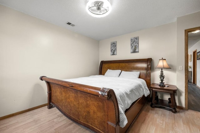 bedroom with baseboards, visible vents, and wood finished floors