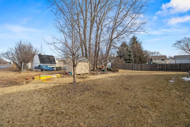 view of yard featuring a storage unit, an outdoor structure, and fence