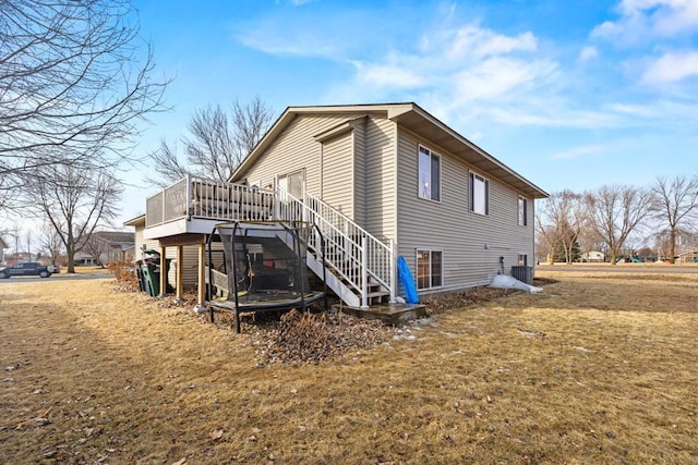 view of side of property featuring central AC unit, stairway, a deck, and a lawn