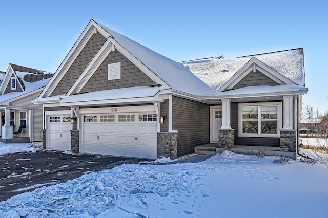 view of front facade featuring stone siding, aphalt driveway, and an attached garage