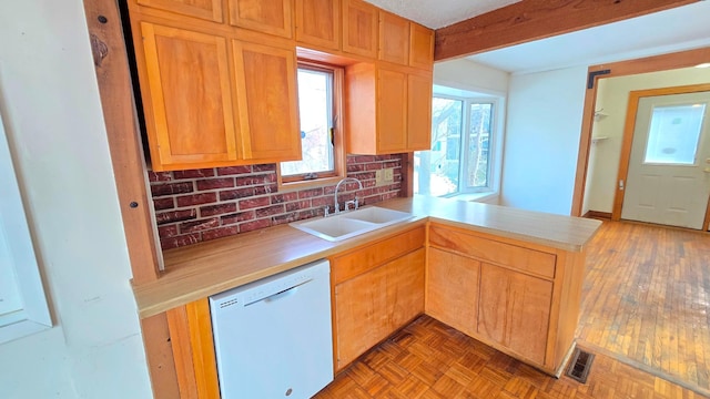 kitchen with parquet flooring, sink, dishwasher, kitchen peninsula, and beamed ceiling