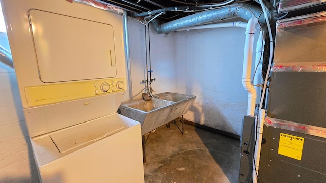 basement featuring heating unit, sink, and stacked washer and dryer