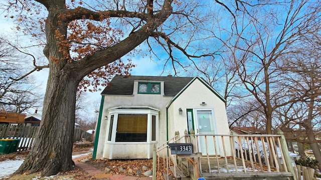 view of front of home with a shingled roof, fence, and stucco siding