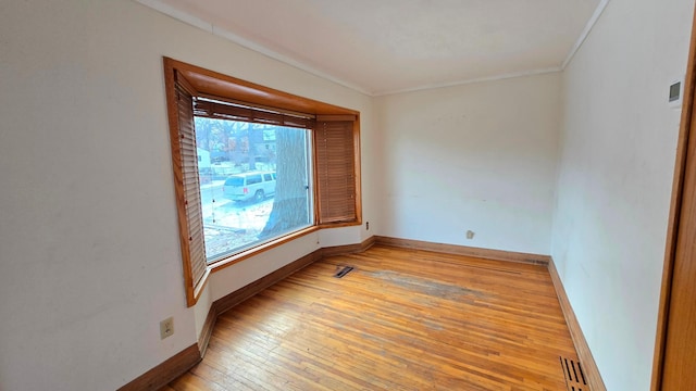 unfurnished room featuring light wood finished floors, visible vents, and baseboards