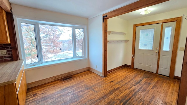 foyer with wood-type flooring, visible vents, and baseboards