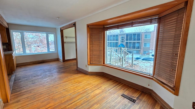 unfurnished room featuring visible vents, light wood finished floors, and baseboards