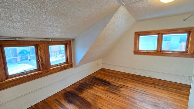 bonus room featuring lofted ceiling, dark wood-type flooring, a textured ceiling, and baseboards