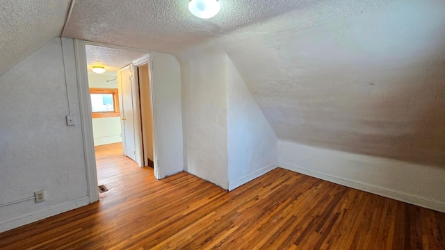 additional living space featuring lofted ceiling, a textured ceiling, and wood finished floors