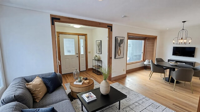 living room with light wood-style floors, a notable chandelier, and baseboards