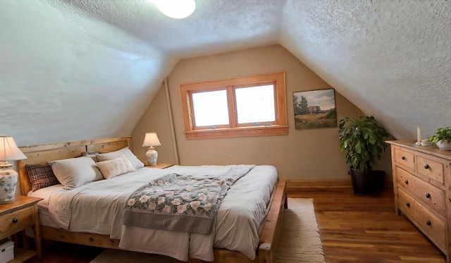 bedroom featuring baseboard heating, vaulted ceiling, a textured ceiling, and wood finished floors