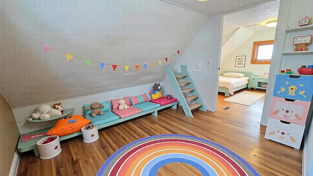 rec room with lofted ceiling, a textured ceiling, and wood finished floors