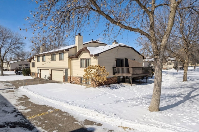 exterior space featuring a wooden deck, a chimney, and an attached garage