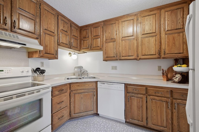 kitchen with brown cabinetry, white appliances, a sink, and under cabinet range hood