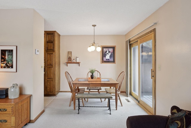 dining space with an inviting chandelier, baseboards, visible vents, and light colored carpet